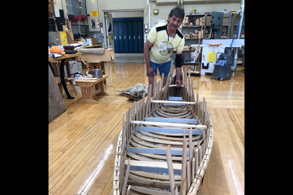 Chuck Commanda, First Nations individual who teachers the art of building birch birk canoes stands by a hand crafted canoe built by five UGDSB students. Supplied photo