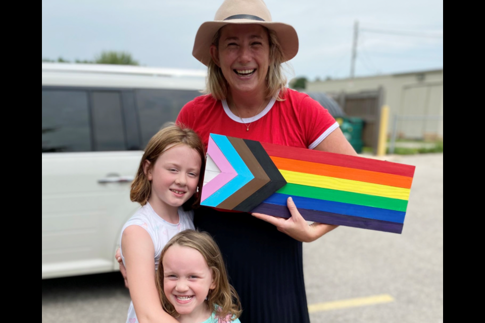 Meg Monsma, kindergarten teacher at Westwood Public School holds the wooden PRIDE flag created by her student Evelyn Blyth and her sister Emily Blyth. Supplied photo
