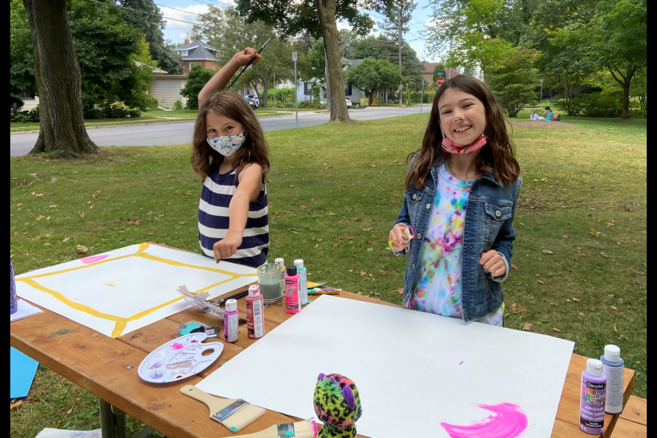 Ten-year-olds Maddy and Ayanna paint signs to put around the neighbourhood so cars can slow down. 