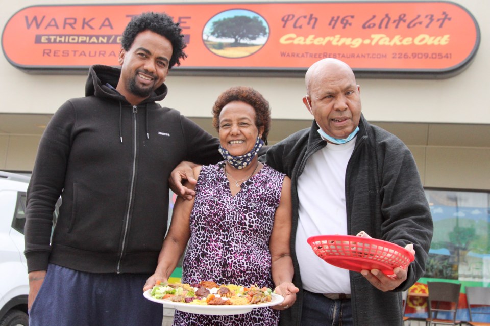 Sentayehu Tessema, centre, holds a Warka Platter in front of The Warka Tree beside her husband Hailu Wakasha (right) and Alex Wakasha (left). 
