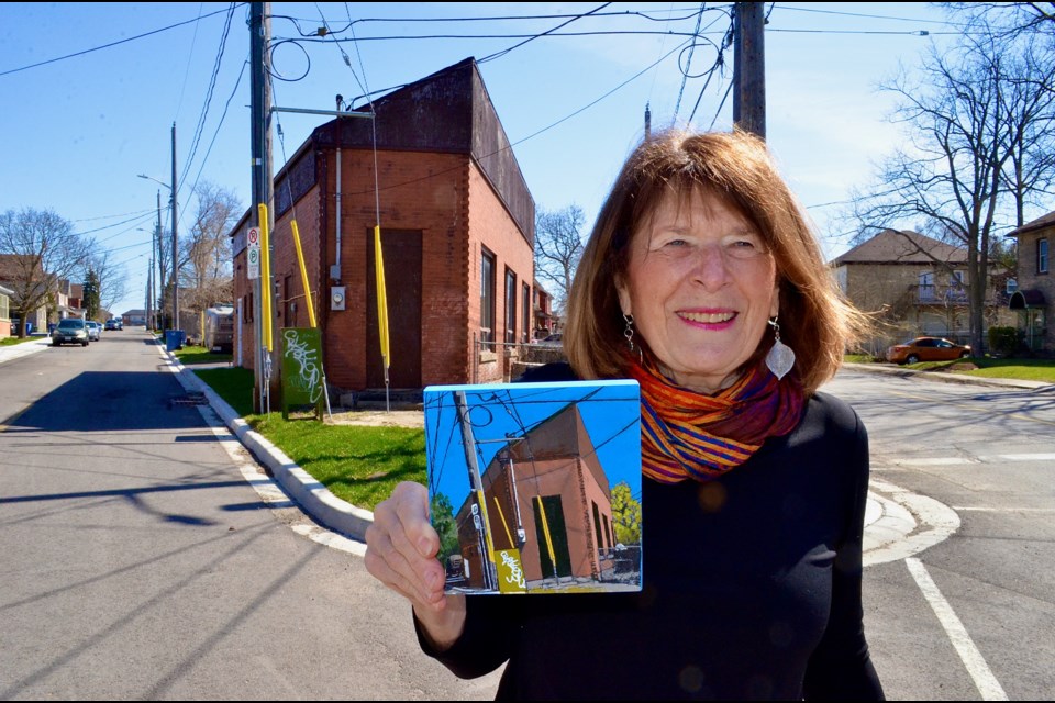 Artist Sharyn Seibert poses with a painting from her Ward Icons series at the corner of Manitoba and Ontario streets.