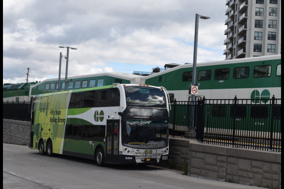 A Metrolinx GO train headed westbound passes a parked GO bus on Monday.