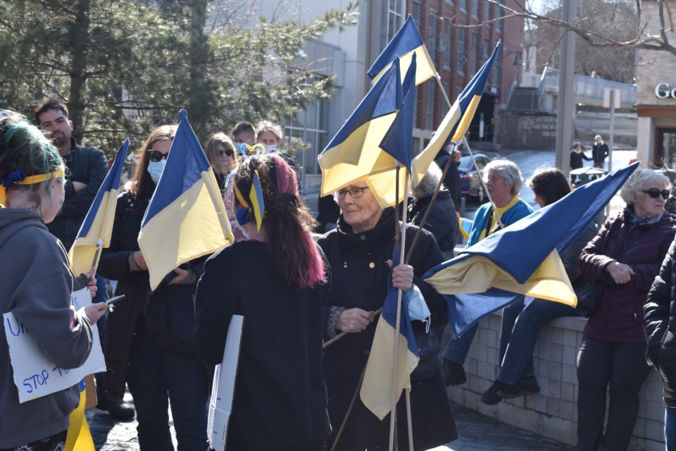 A woman shares Ukrainian flags with those at the rally.