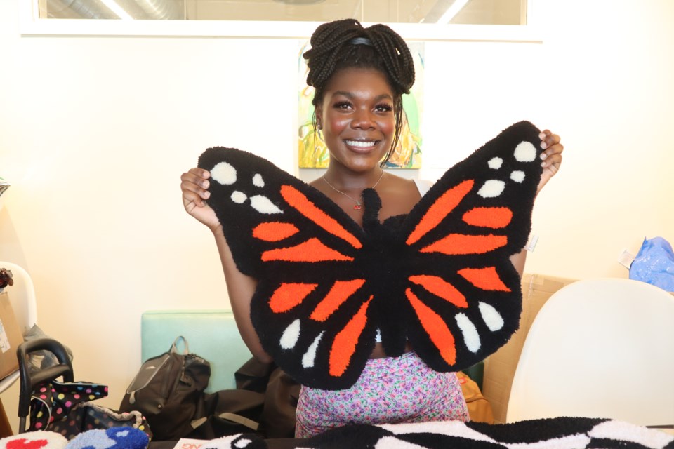 Britany Wasswa, owner of The Ruggery, holding up a butterfly rug she made.