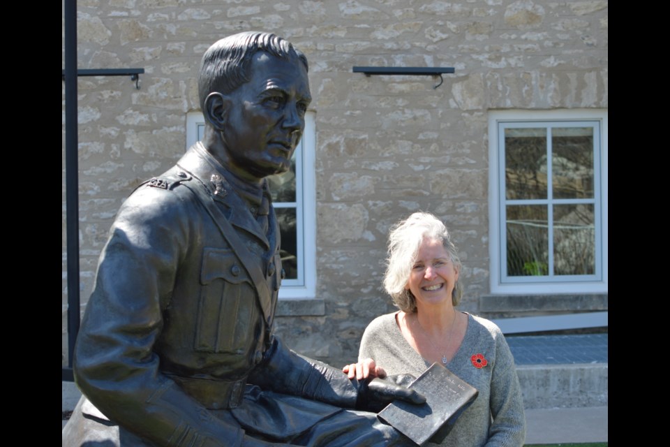 Val Harrison standing with the John McCrae statue