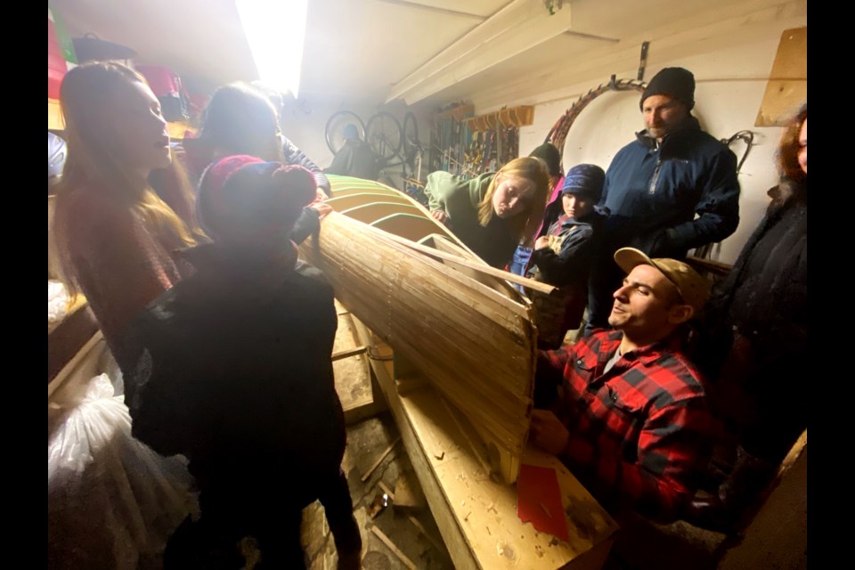 Children working on the canoe and the girl who started it all, Rowan Craig, in the green sweater, working on the canoe.