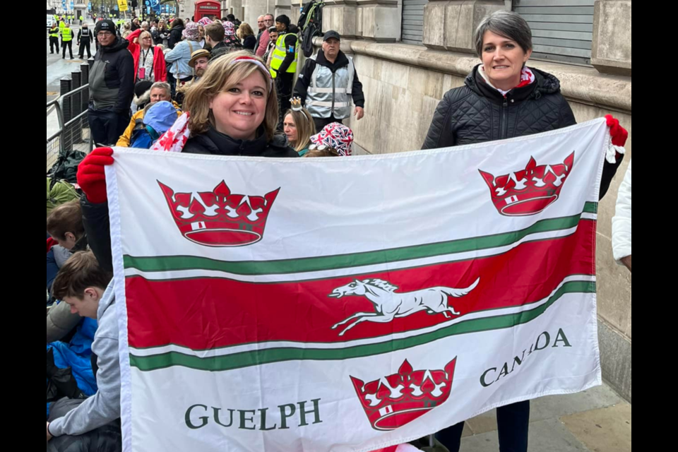 Sisters Michela Zamprogna and Paola Case near Trafalgar Square in London, England holding the Guelph flag while waiting for the King and Queen to pass by.