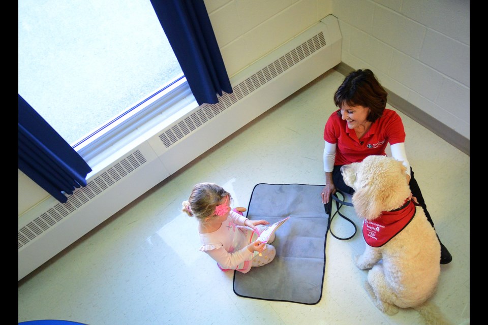 Madison, 5, sits with Wendy Eastman and therapy dog Fergus at Westwood Public School. Tony Saxon/GuelphToday