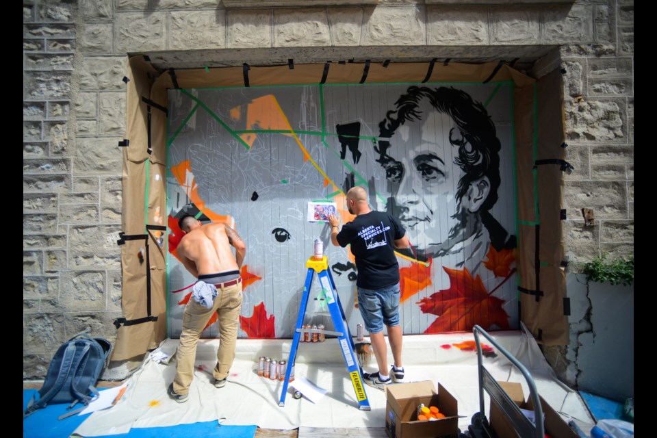 Alex Kwong, left, and Sergey Ryutin work on their mural on the side of City Hall Saturday. It's one of four coming to Downtown Guelph this fall. Tony Saxon/GuelphToday