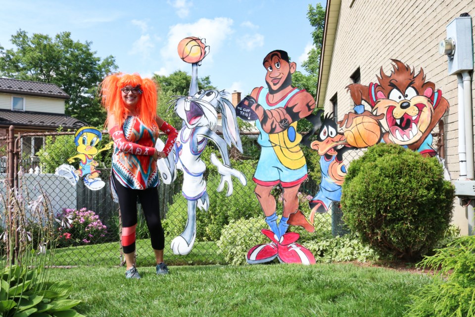 Dorothy Amey, left, standing with some of the characters from Space Jam she painted and placed on the fence on her property. Ariel Deutschmann/GuelphToday