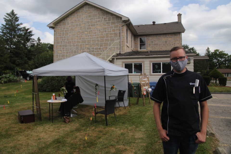 Gianluca Prigione is a barber at Freddy's Hairstyling, which has been at 414 Eramosa Road since 1973. The business has set up a tent in the backyard for clients who would prefer their hair be cut outdoors. Kenneth Armstrong/GuelphToday