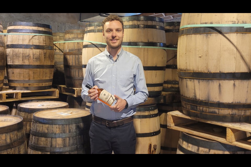 Cooper Sleeman, manager of sales and marketing at Spring Mill Distillery, holds a bottle of their new traditional straight whiskey, set to be released Friday.