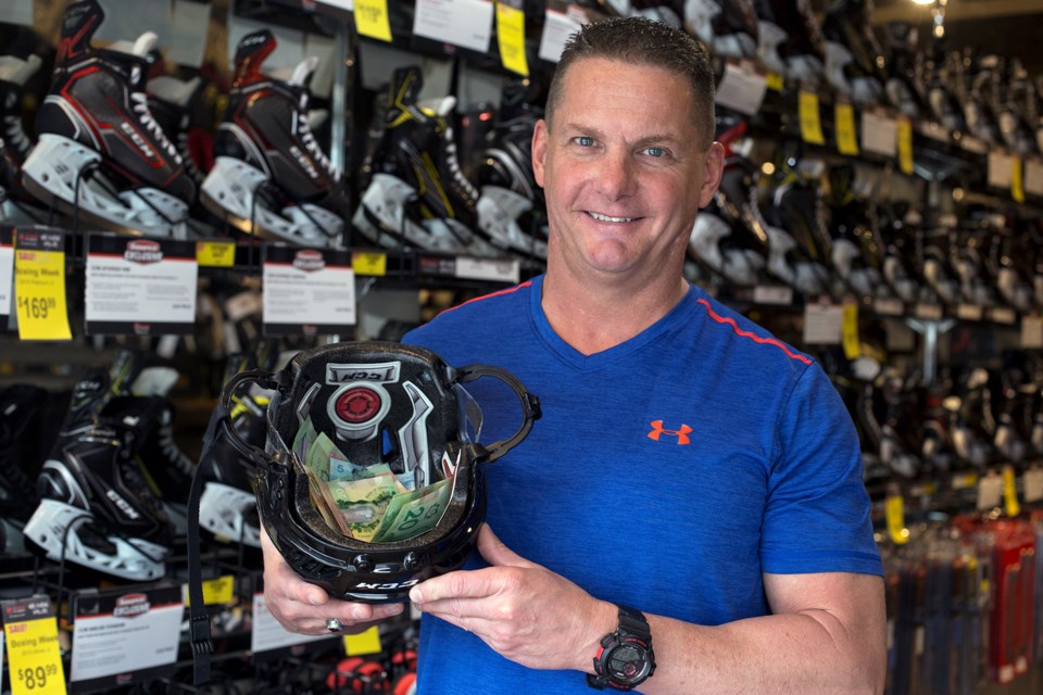 Todd Gumbley, owner of Hockey Shop Source for Sports, holds up a helmet with donations made by customers in support of the victims and families of the devastating bus crash in Saskatchewan. Kenneth Armstrong/GuelphToday