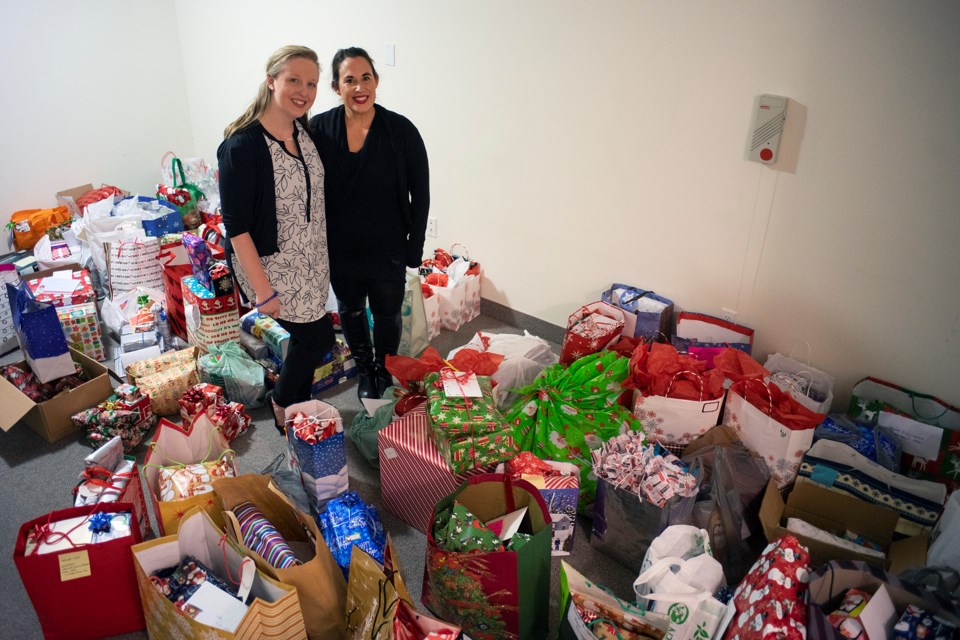 Adopt-a-Senior co-organizers Kayla McQueen and Kyla Rowntree  pose in a room at the Village of Riverside Glen filled with just some of the donations made through the program in its first year. Kenneth Armstrong/GuelphToday