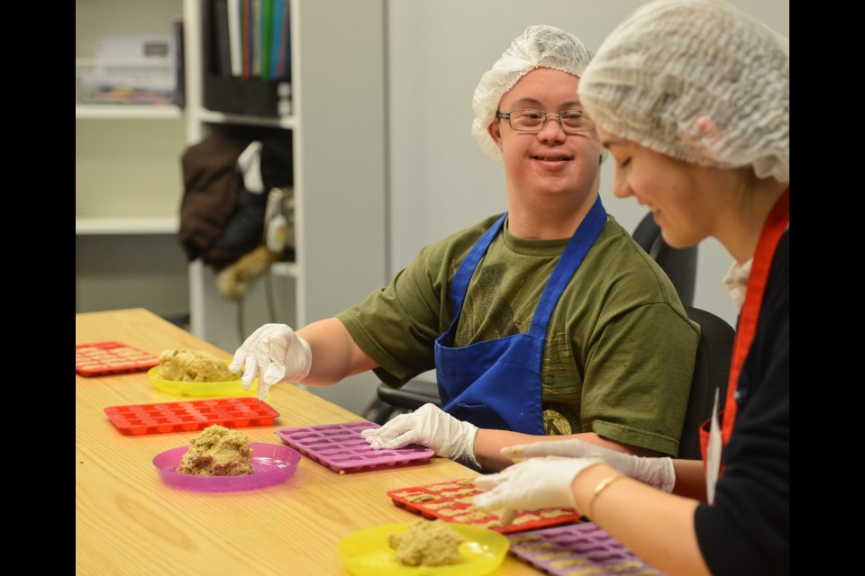 Duncan shares a laugh with a volunteer as he makes dog treats in the Boxes of Hearts program at Choices of Hearts in Old Quebec Street Mall. Tony Saxon/GuelphToday
