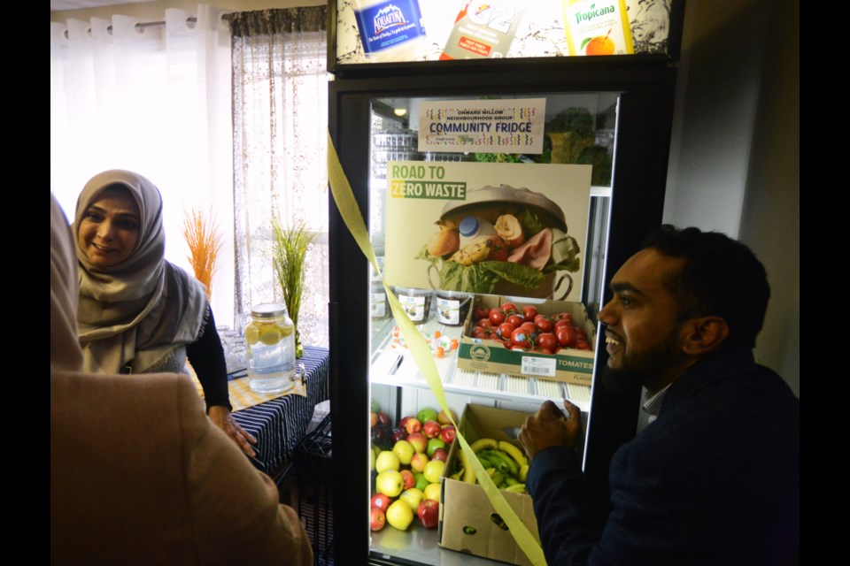 Road To Zero Waste creators Laylo Atakhodjaeva and her husband Shabeeb Hasan fill the new community food fridge at Onward Willow Community Centre Saturday. Tony Saxon/GuelphToday