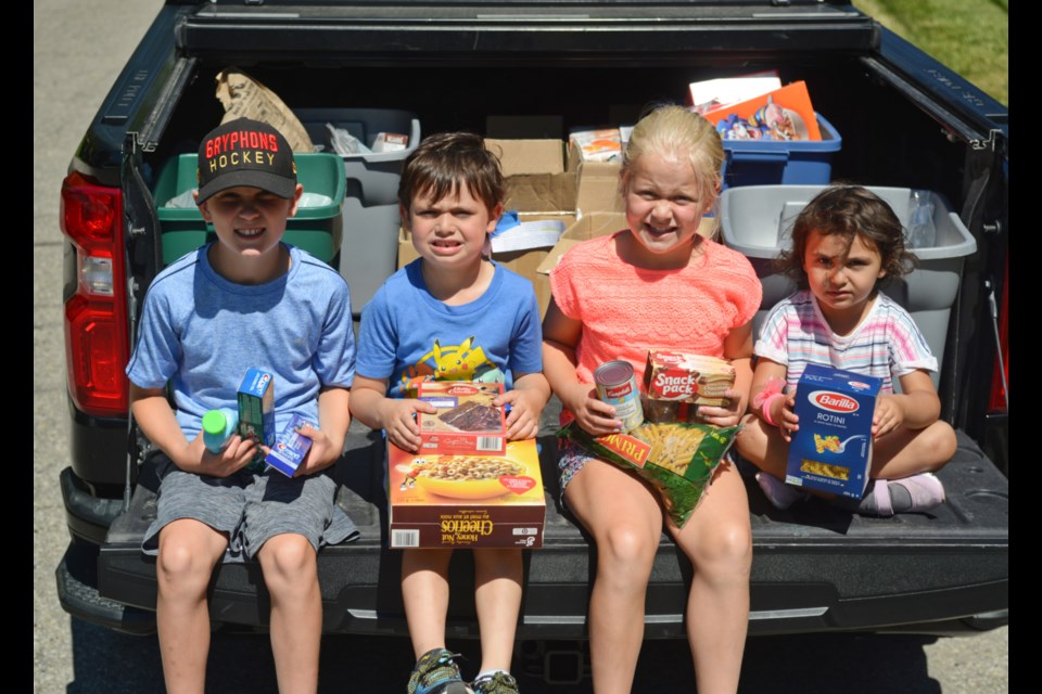 Jack Roadknight, from left, Elias Roadknight, Julia Roadknight and Aiya Roadknight sit with some of the 180 kg of food they collected Tuesday for the Guelph Food Bank. Tony Saxon/GuelphToday