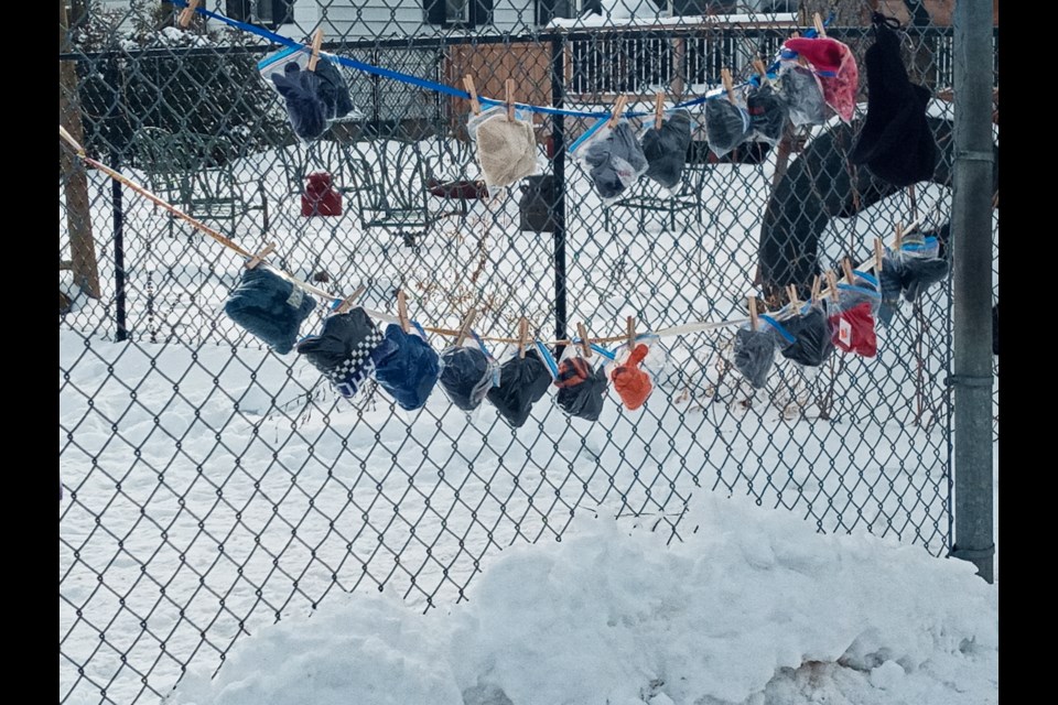 Bags of mittens and hats hang on a fence along Edinburgh Avenue for #projectwarmth. Supplied photo