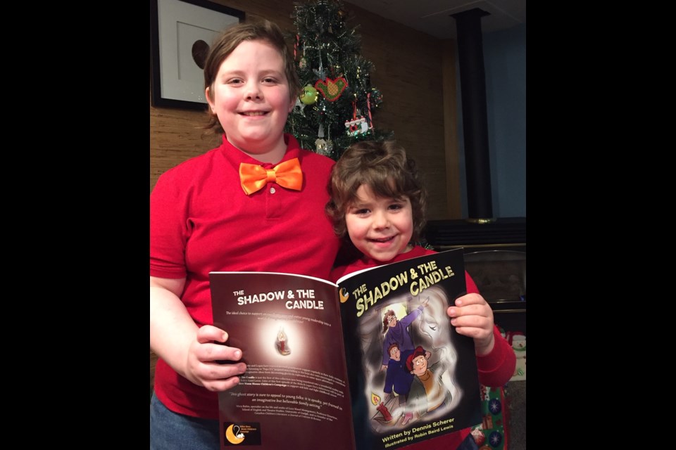 Scherer's grandsons, Blake, left, and Logan, right, hold up a copy of The Shadow and The Candle. Supplied photo