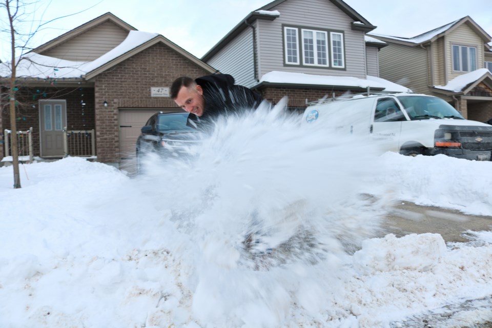 A volunteer for Snow Angels, Andrew Neilson, sends a big heap of snow flying while snow shoveling.