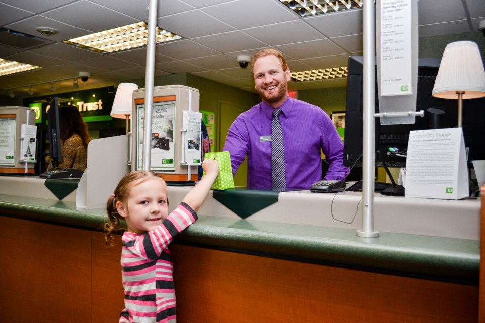 Bailee makes her deposit with Addam, a customer service representative at TD Bank. Photo by Daniel Bell for GuelphToday.  