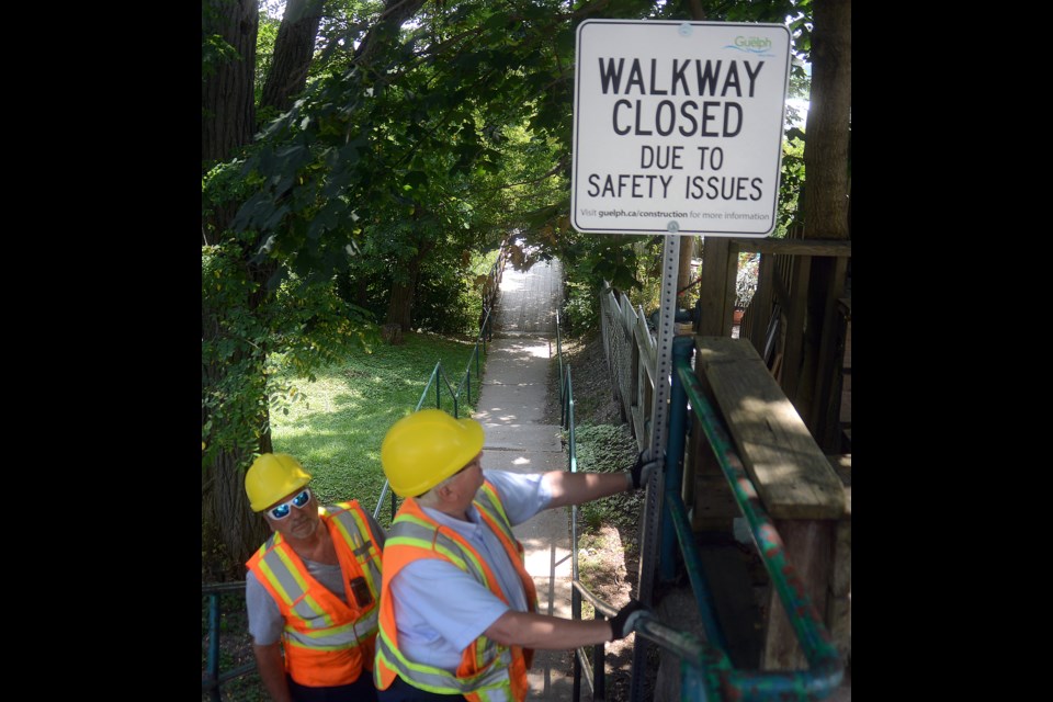 City workers install a sign Tuesday, Aug. 1, 2017, at the 100 steps walkway between Elizabeth Street and Grove Street after the city closed it for safety reasons. Tony Saxon/GuelphToday