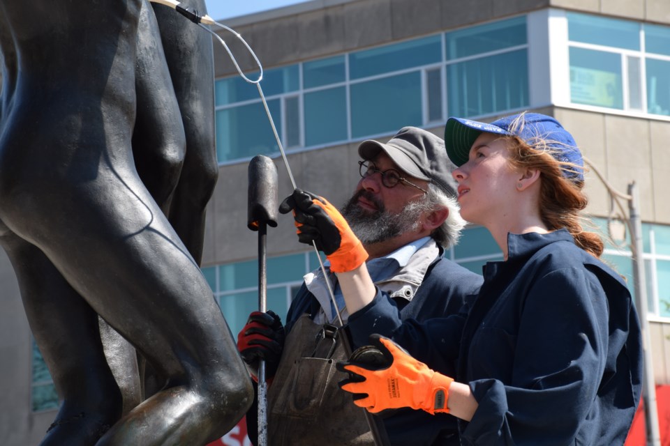 Anna Bullock, assistant to art conserver and restorer Alexander Gabov, applies the finishing touches to "The Family." Rob O'Flanagan/GuelphToday