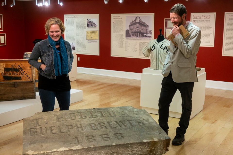 Dawn Owen, Guelph Civic Museum curator, and guest curator Eric Payseur speak next to a name stone for the former T. Holliday Guelph Brewery, which closed in the 1930s and was demolished in the 1980s. The stone is one of a number of artifact's in the museum's upcoming exhibit Brewing Changes Guelph. Kenneth Armstrong/GuelphToday