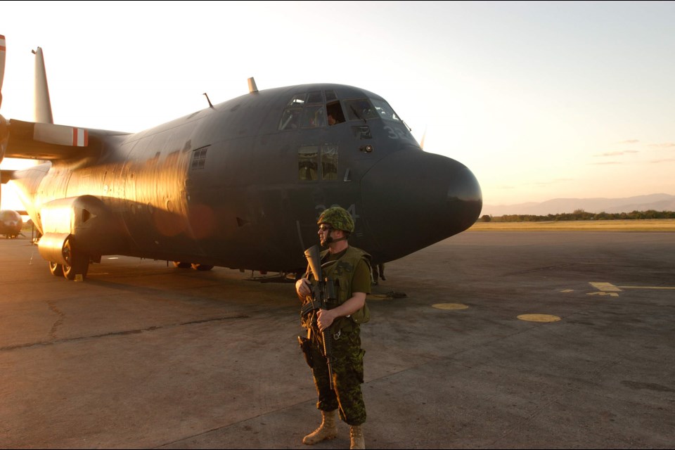 Canadian soldier guards C-130 while waitijng for evacuees in Latin America.