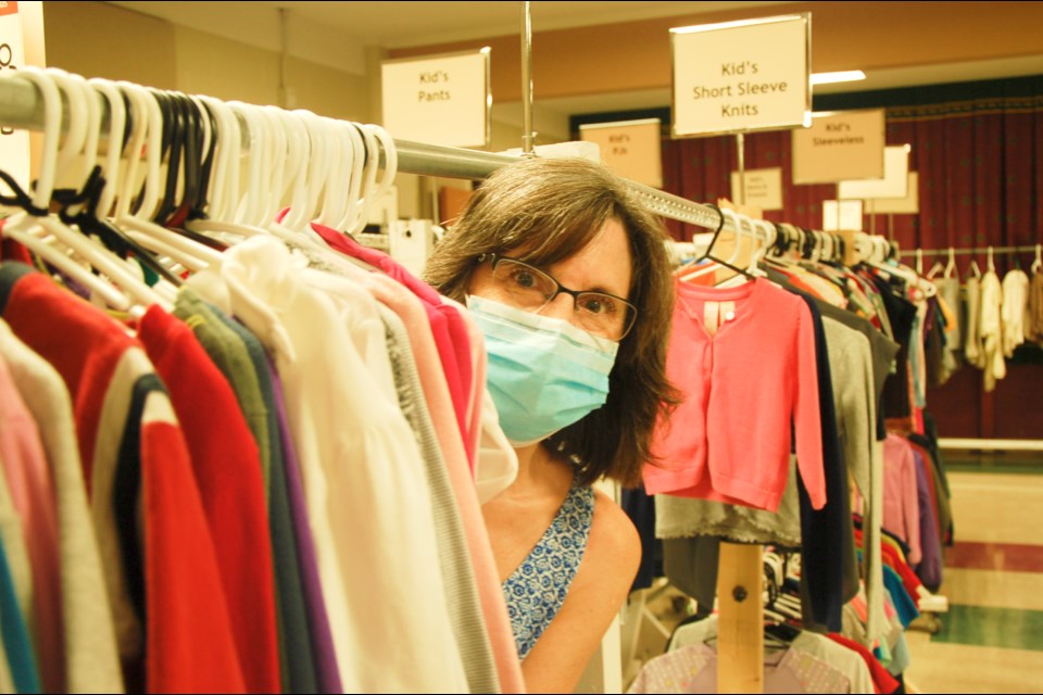 The Clothing Closet coordinator Lisa Burke peeks through a clothing rack.