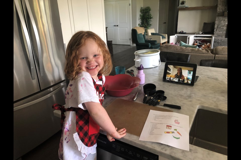 A child following a recipe from 'Plant-Based Proteins: Recipes Made Easy-Peasy' at home.