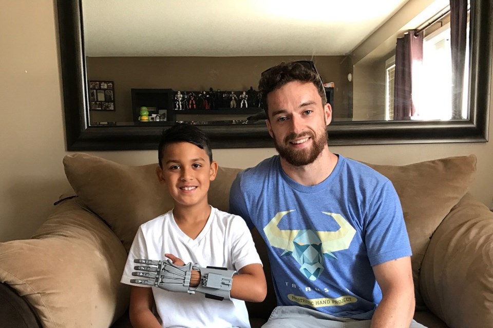 Jerry Ennett poses for a photo with Jordan, a boy who uses a prosthetic hand designed by Ennett. The prosthetic can be built for about $25 worth of materials. Photo provided