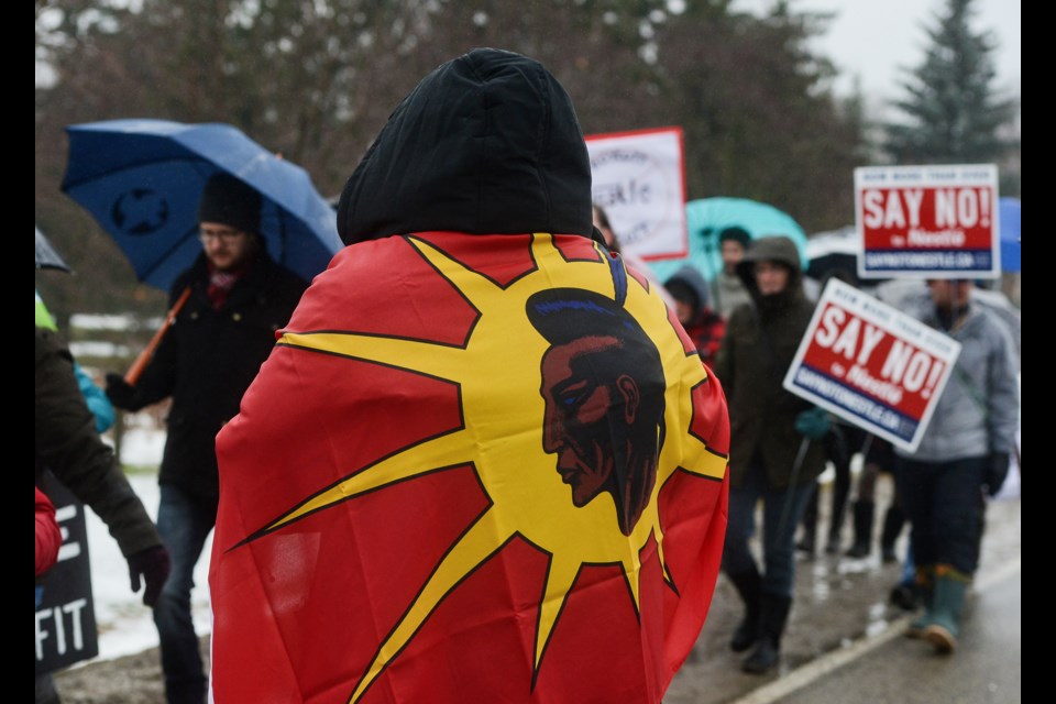 Indigenous activist Eryn Wise, with a First Nations flag around her shoulders, watches the procession of protesters make its way to the Nestle plant in Aberfoyle on Saturday. Tony Saxon/GuelphToday