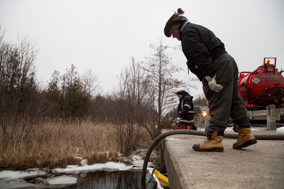 John Johnston (foreground) watches as an effort is made to clean up jet fuel on his property on Concession 2 near Sideroad 20 S in Puslinch Township. The Ministry of the Environment is overseeing clean up efforts, which resulted from a tanker rollover on the 401 on Sunday. Kenneth Armstrong/GuelphToday