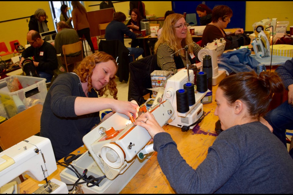 Everywear owner and seamstress Jennifer Blender, left, opens up a sewing machine to get at the thread of the problem. Blender was one of 15 repair people for the third Repair Cafe. Rob O'Flanagan/GuelphToday
