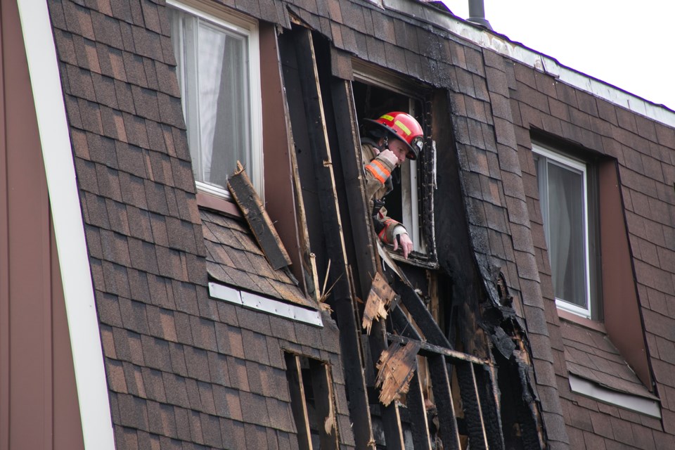 A firefighter peers out the upstairs rear window of 39 Dovercliffe Road, the scene of a house fire Tuesday afternoon. Kenneth Armstrong/GuelphToday
