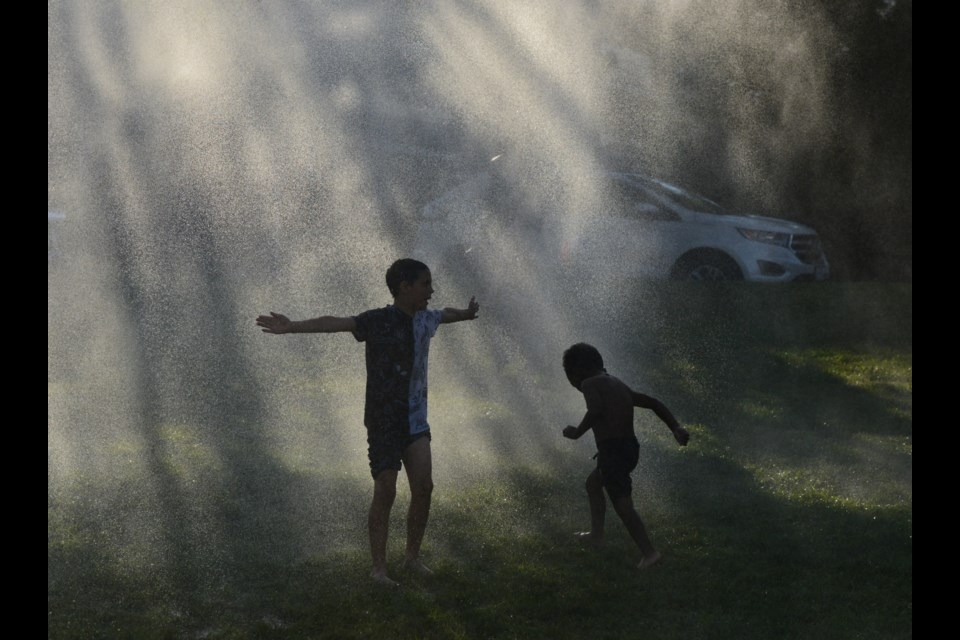 Children play in the water provided by the Guelph Fire Department at Margaret Greene Park Thursday on the first Hot Summer Nights event.