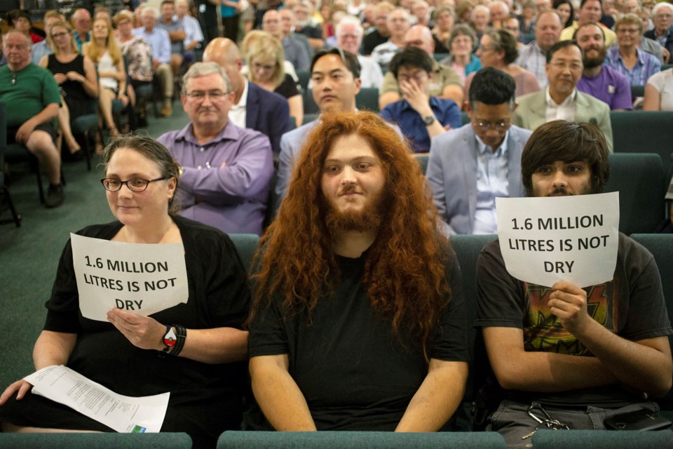 People hold signs in opposition to a proposed float glass plant during a meeting of Guelph/Eramosa Township council Monday at Parkwood Gardens Community Church in Guelph. Kenneth Armstrong/GuelphToday