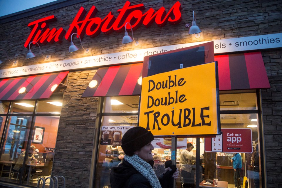 Donna Jennison walks in front of the Tim Hortons on Victoria Rd. S. during an action in solidarity with workers of the chain, many of whom have received a cut to benefits and breaks in light of an increase in minimum wage. Kenneth Armstrong/GuelphToday