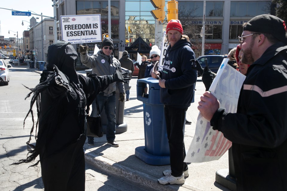 A Guelph woman dressed as the Grim Reaper in a verbal exchange with an anti-mask protester reaches out for a hug during a 'COVID is Over' rally at St. George's Square on Sunday. Kenneth Armstrong/GuelphToday