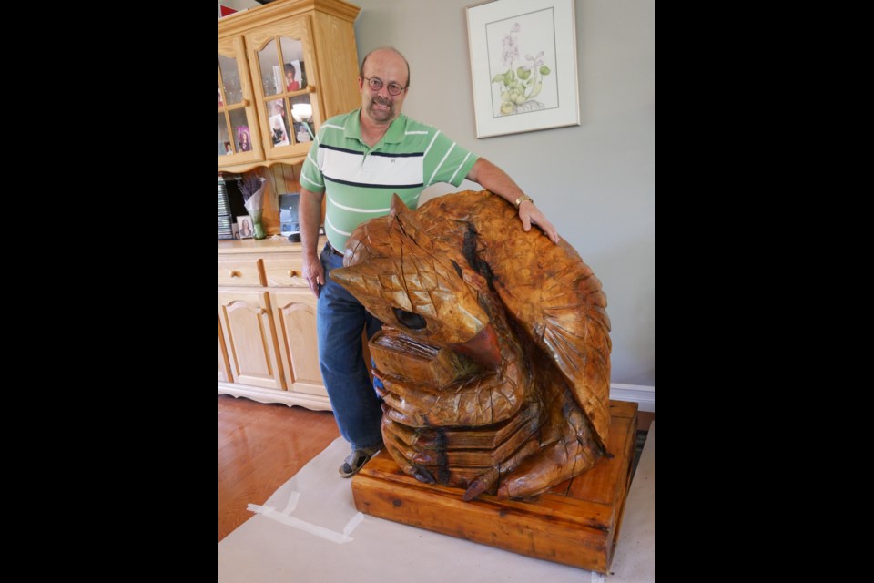 Rod Merrill stands besides the gryphon statue in his living room. Supplied photo