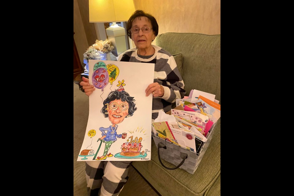 Rita Cardow poses with a caricature and some of the birthday cards she has received from residents for her 100th birthday.