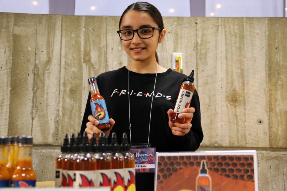 Krupa Thakkar holding U of G's Cannon Fire hot sauce and Hot Honey. 