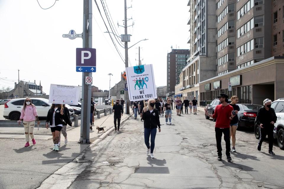 About 60 demonstrators, many representing local restaurants, hair salons and MMA gyms, march down Baker Street on Saturday. Kenneth Armstrong/GuelphToday