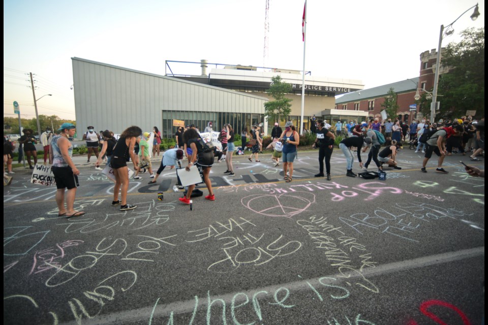 Protesters paint and chalk slogans on Wyndham Street in front of police headquarters Wednesday at the The Guelph Black and Indigenous Solidarity Rally Against Police. Tony Saxon/GuelphToday