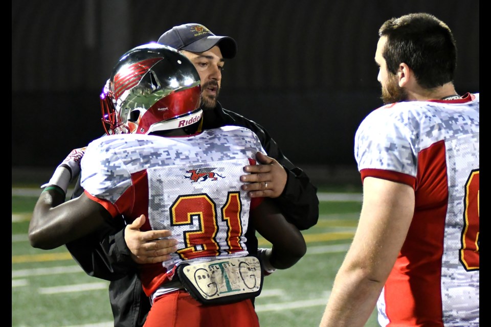 Interim head coach Kevin MacNeill of the Guelph Gryphons hugs running back Patrick Pierre (31) while Daniel Urbshas waits his turn following the end of the Gryphons season. They were ousted from the OUA football playoffs with a quarter-final loss to the McMaster Marauders Saturday at Hamilton. Rob Massey for GuelphToday