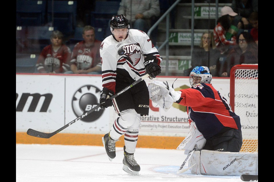 The Guelph Storm's Zach Poirier gets hit by a point shot as he tries to screen Windsor Spitfires goaltender Michael DiPietro Friday, Oct. 6, 2017, at the Sleeman Centre. Tony Saxon/GuelphToday