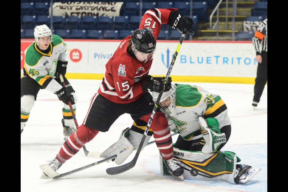 Braeden Bowman of the Guelph Storm tries to top a point shot past London Knights goaltender Owen Flores.