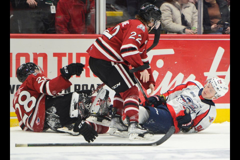 The Guelph Storm's Ben McFarlane comes to defend teammate Cooper Walker after a hit along the boards by Windsor's Oliver Peer Friday at the Sleeman Centre.