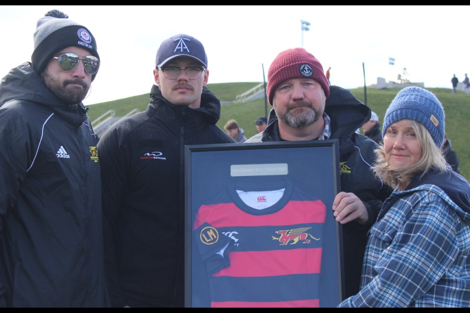 University of Guelph men's rugby assistant coach Aria Keshoofy, left, presents a framed Gryphons rugby jersey to the family of Luke MacDonald. Luke's brother Gavin, and parents Mike and Kelly were on hand for the ceremony.